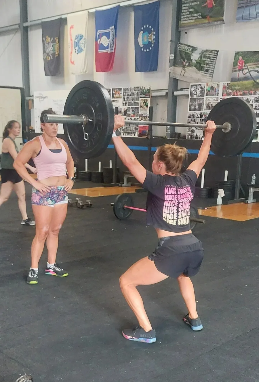 Athlete performing an overhead barbell lift inside the Cynergy Training gym