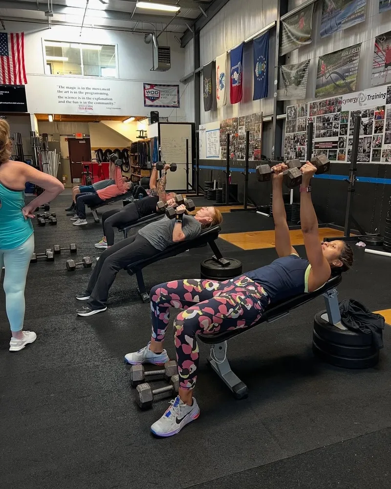 Members performing dumbbell bench press during a class