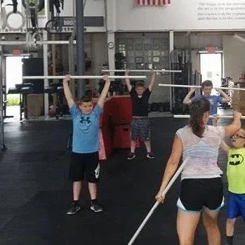 Kids performing overhead PVC pipe drills at Cynergy Kids class