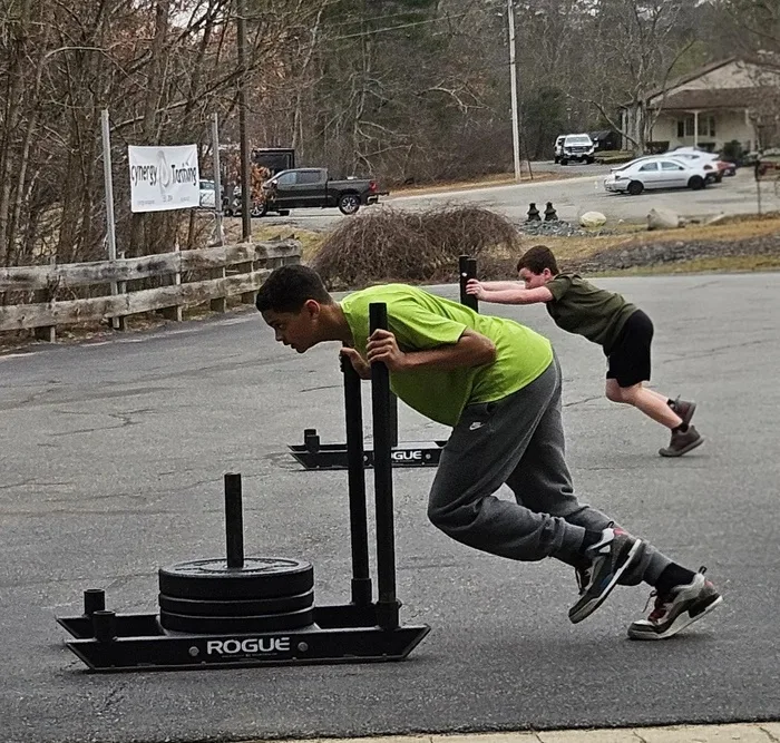 Youth athletes pushing a weighted sled outdoors